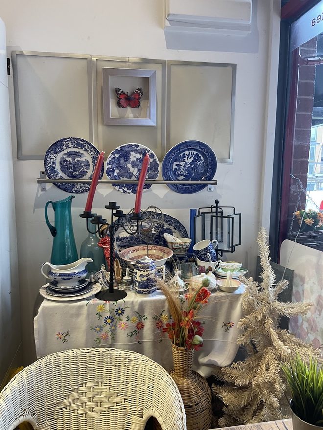 A decorative corner with a lace-covered table, china plates and a cake stand